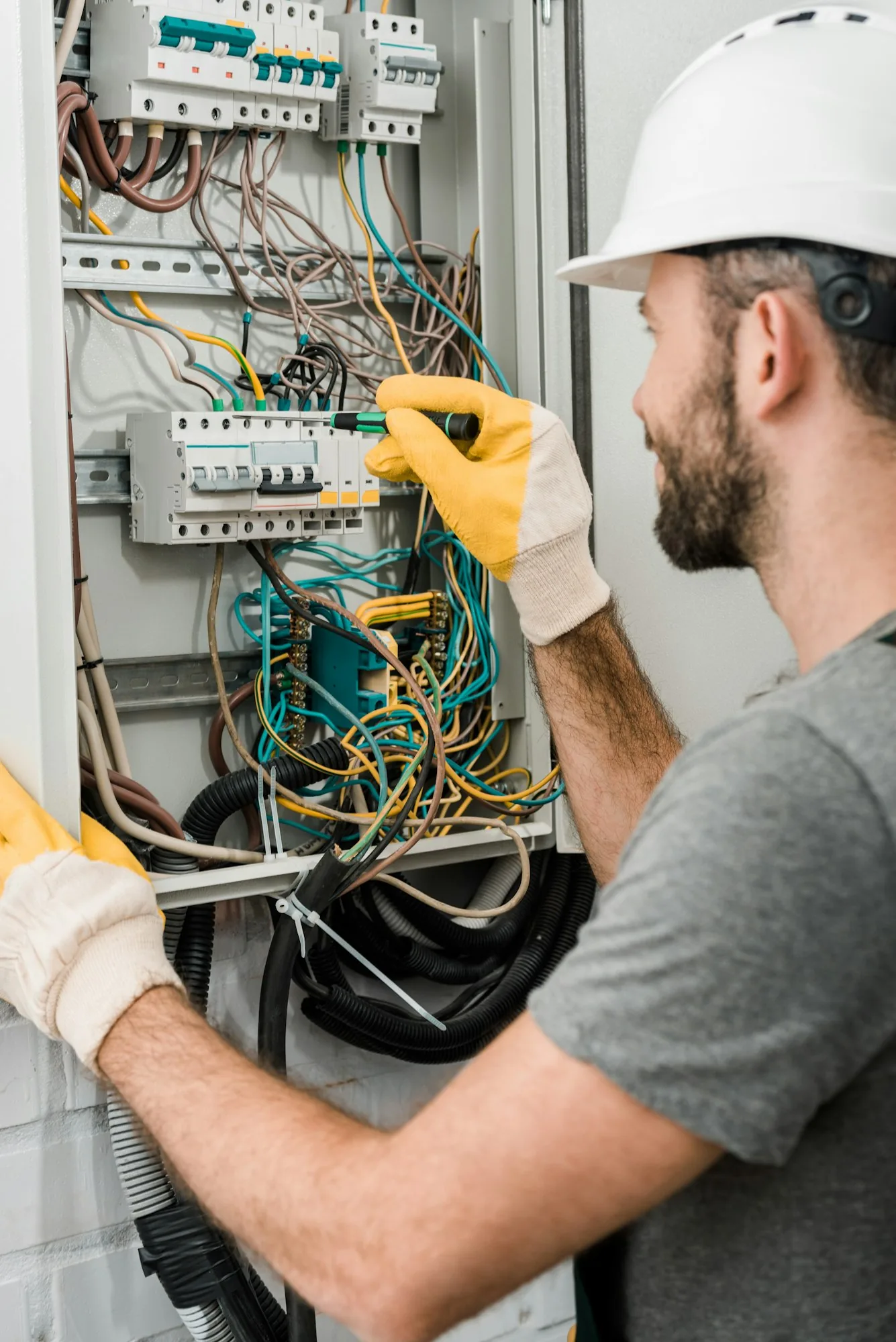 Elpro Electric electrical work: side view of electrician repairing electrical box and using screwdrive