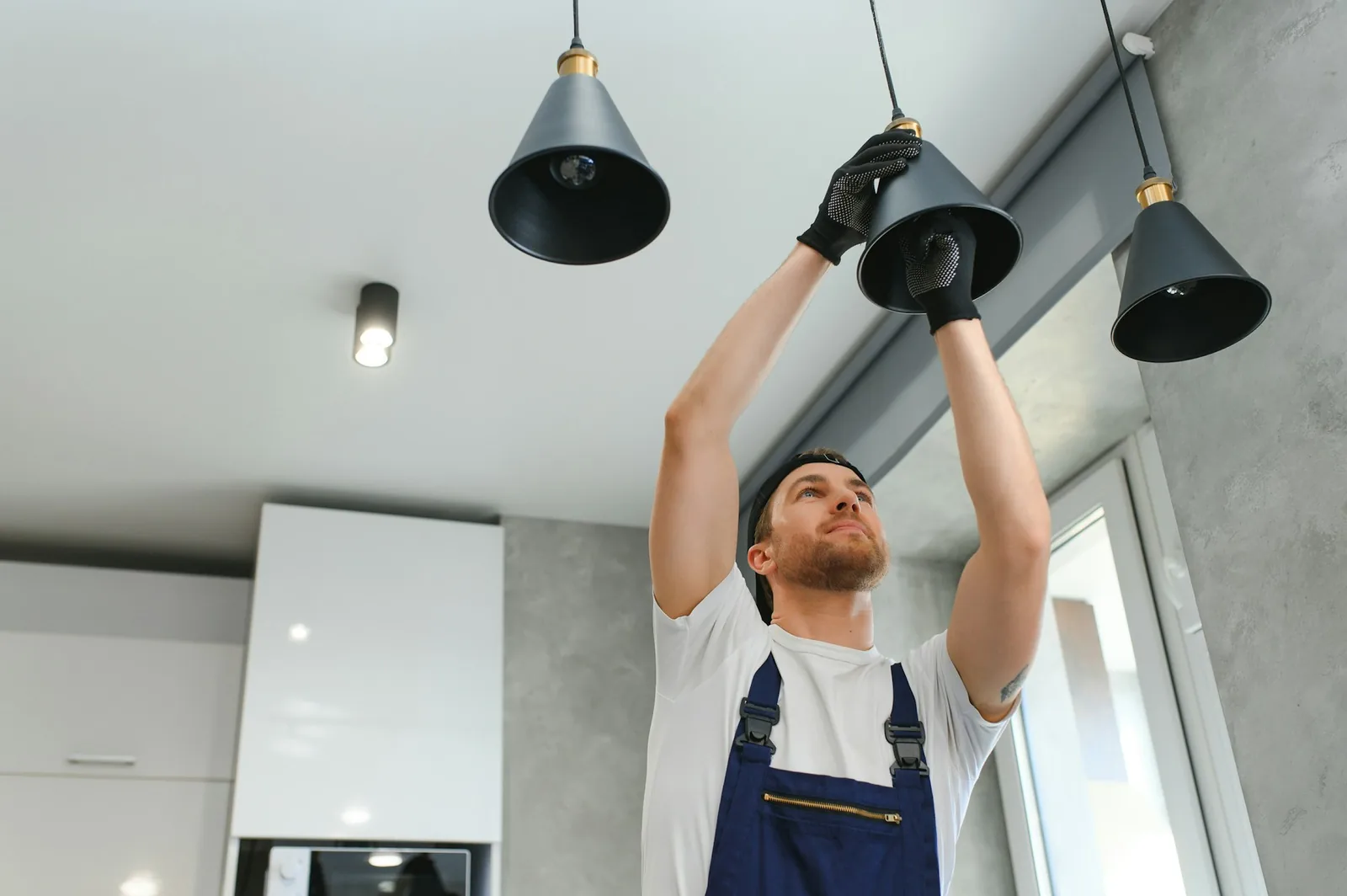 Lighting installation - a male electrician changes the light bulbs in the ceiling light men s