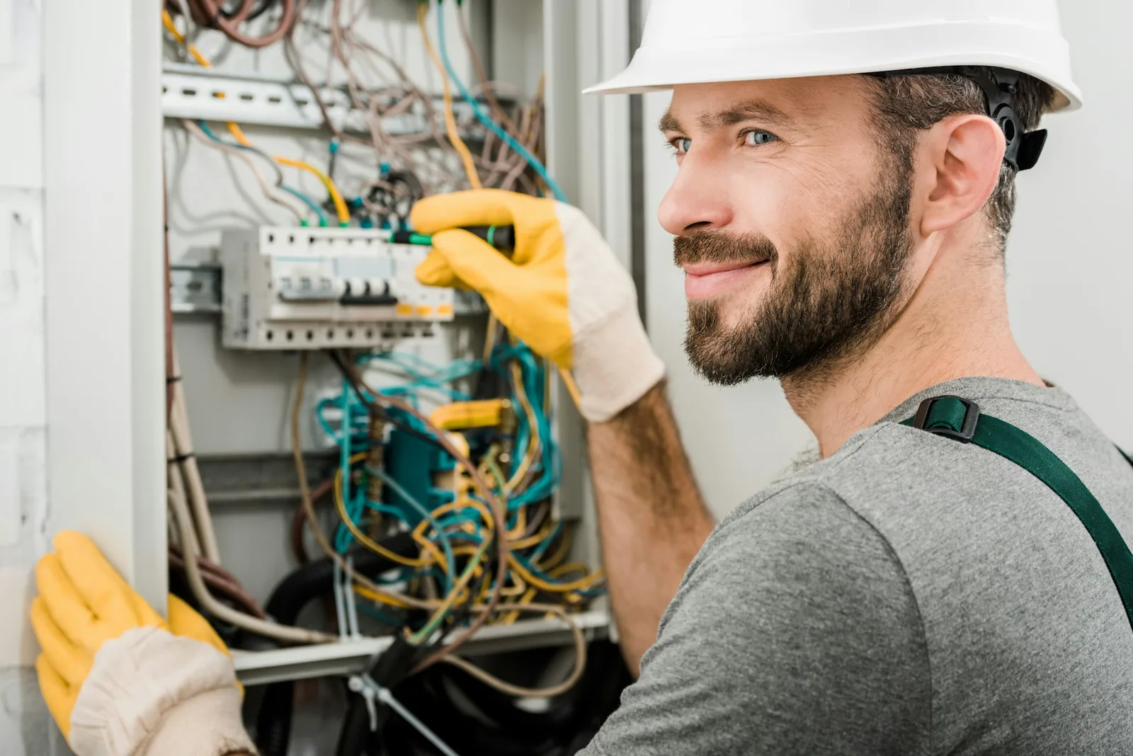 Standby generator installation - handsome cheerful electrician repairing electrical box and using screw