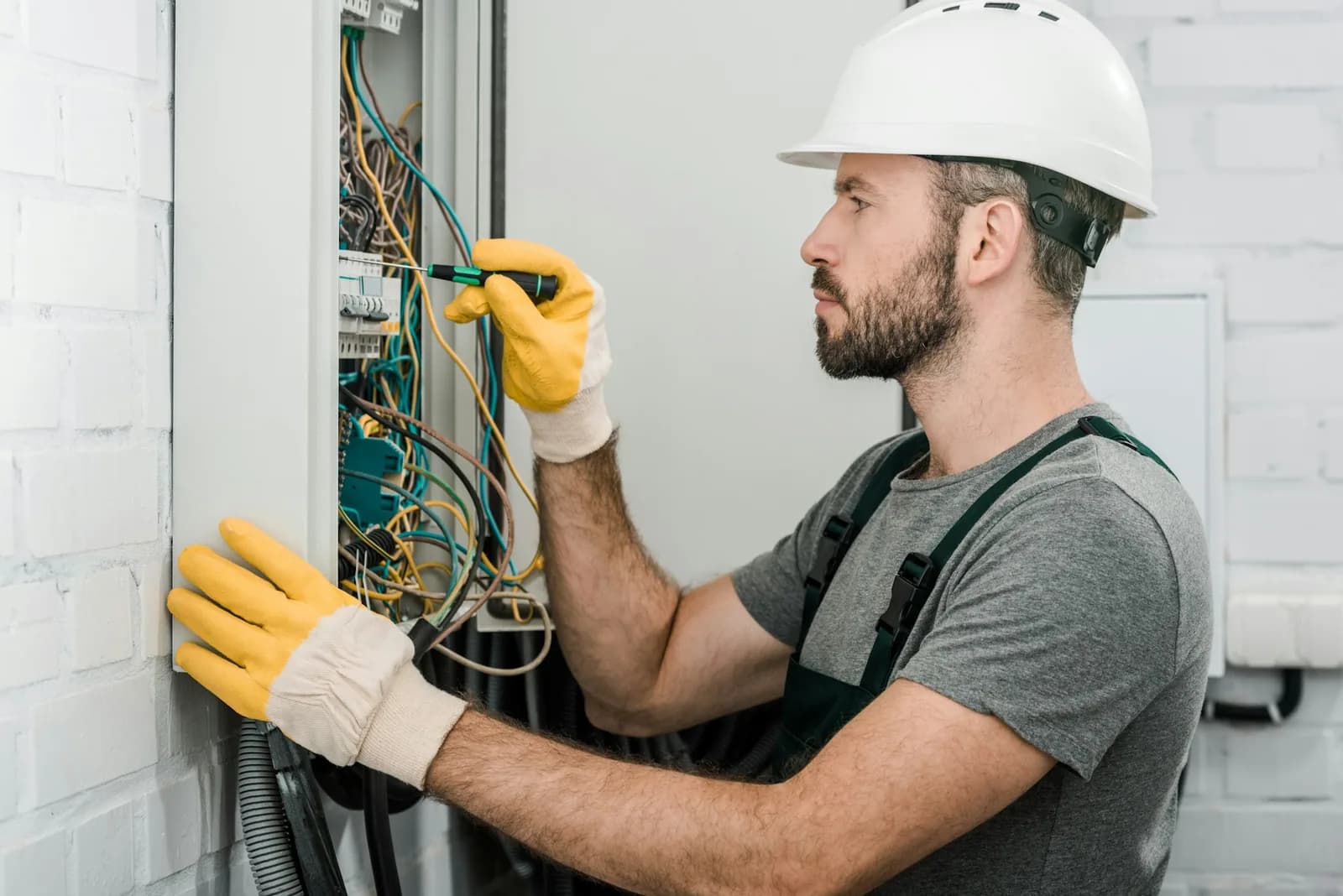 Standby generator installation - side view of handsome bearded electrician repairing electrical box and
